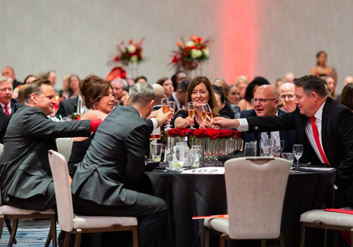 Table full of guests toasting glasses together.